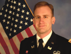 A photo of Wayne Johnson in his dress uniform in front of an American flag.